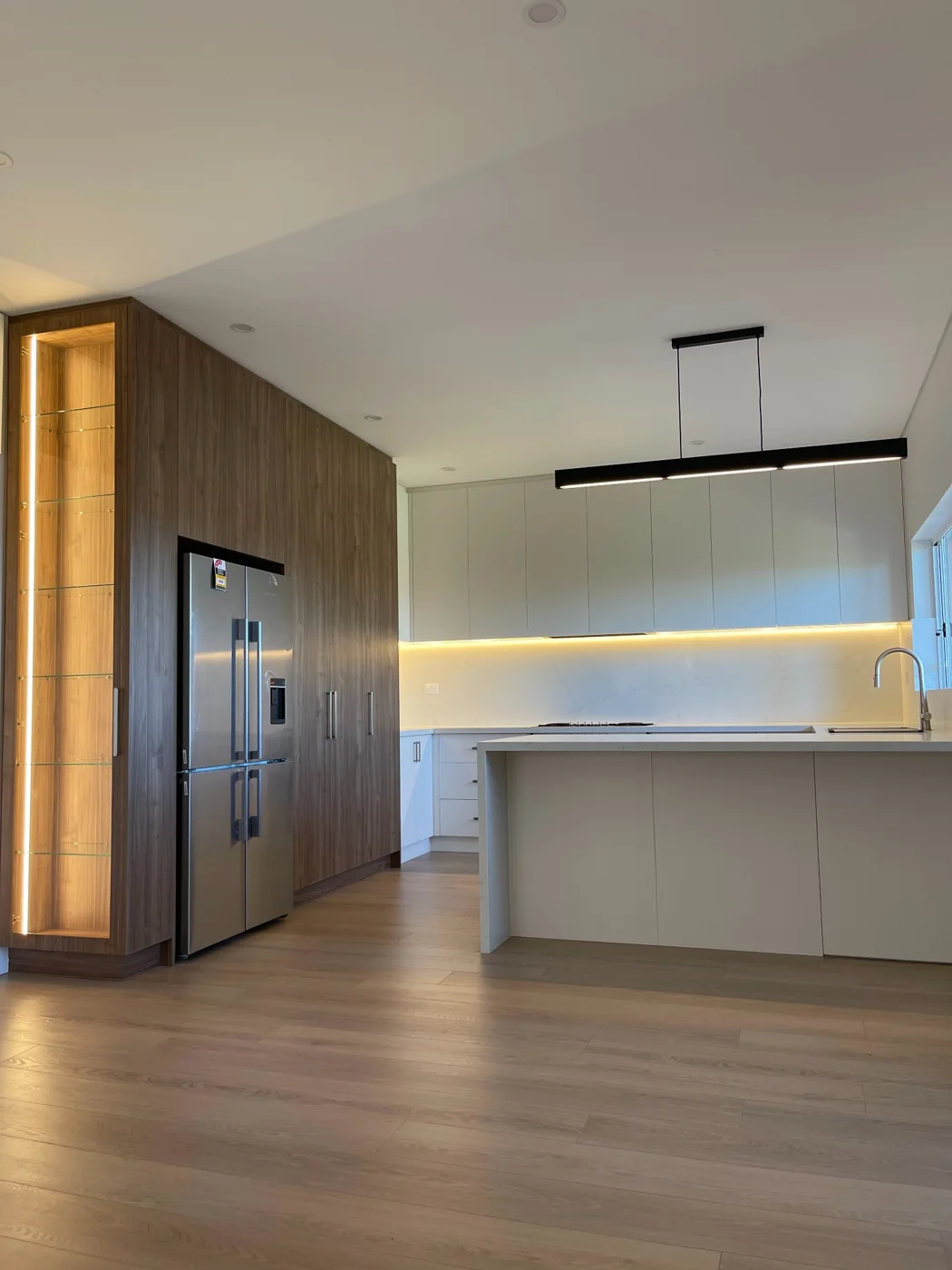 Kitchen with linear pendant and illuminated cabinetry